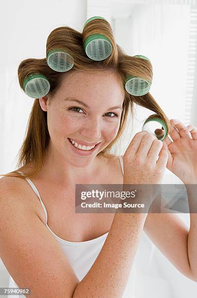 young woman putting curlers in hair - curling stock pictures, royalty-free photos & images