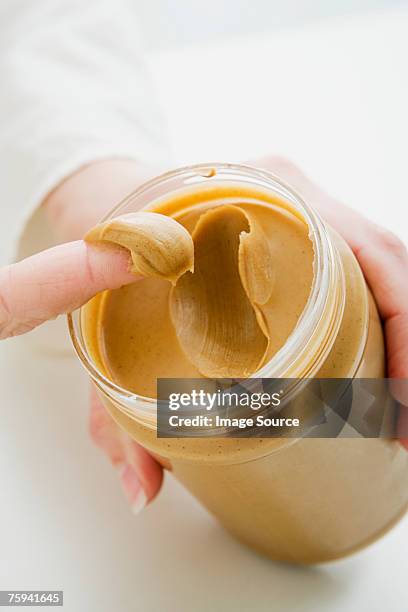 woman scooping peanut butter from jar - pindakaas stockfoto's en -beelden