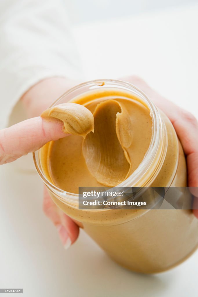 Woman scooping peanut butter from jar