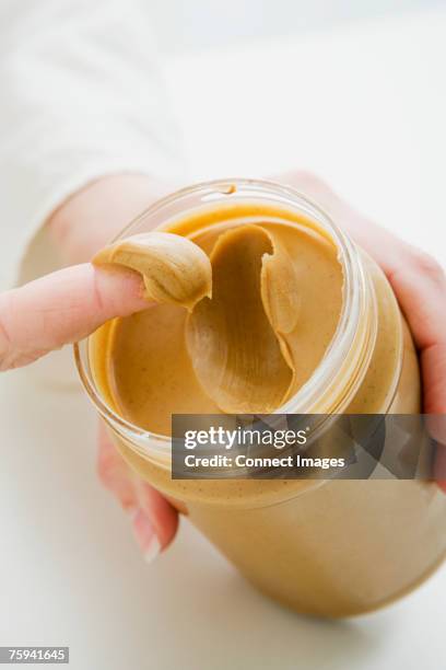 woman scooping peanut butter from jar - peanut butter stock pictures, royalty-free photos & images