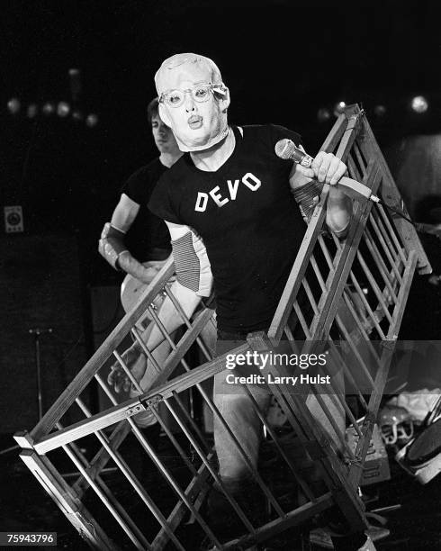 Mark Mothersbaugh of the punk new wave group "Devo" wears a maks and holds a crib around him as he performs onstage in circa 1977.