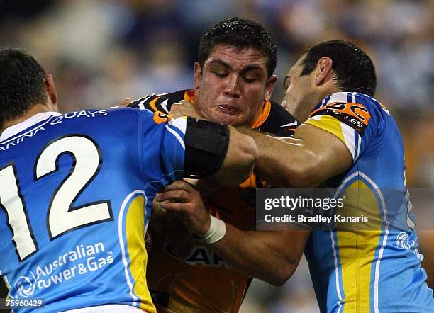 Chris Heighington of the Tigers attempts to break through the Titans defence during the round 21 NRL match between the Gold Coast Titans and the...