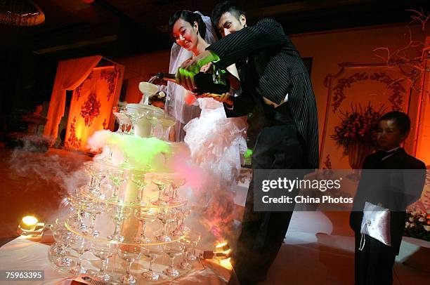 Models dressed as a newlywed couple pour champagne into a Champagne tower during a wedding expo at the Hotel Shangrila August 4, 2007 in Beijing,...