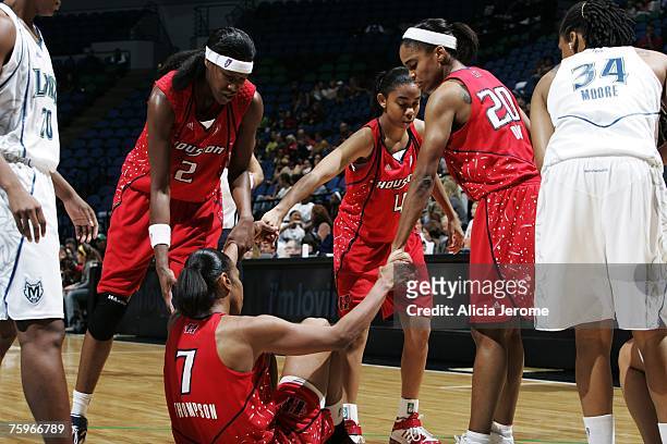Michelle Snow, Erin Grant and Tamecka Dixon all of the Houston Comets help up teammate Tina Thompson during a game against the Minnesota Lynx on...