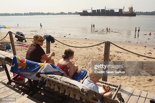 Container ship passes beachgoers on the Elbe River on its way to Hamburg August 4, 2007 at Wedel, Germany. Northern Germany, with its busy ports of...