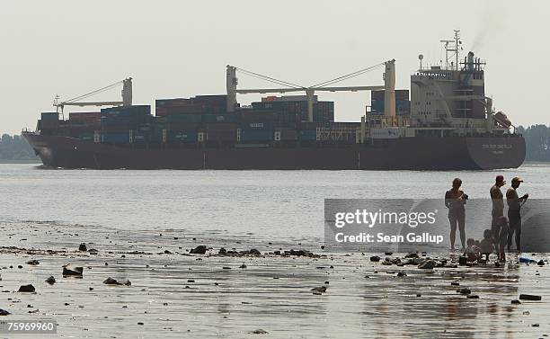 Container ship passes beachgoers on the Elbe River on its way to Hamburg August 4, 2007 at Wedel, Germany. Northern Germany, with its busy ports of...