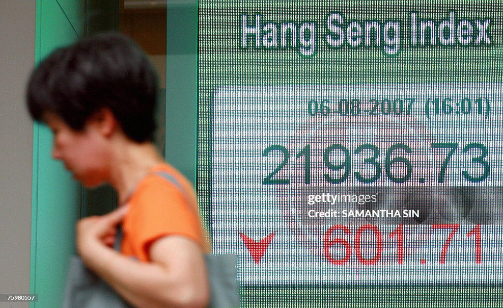 A passerby walks past the Hang Seng Inde