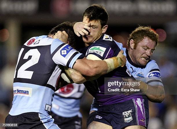 Ben Cross of the Storm is tackled by Craig Stapleton and Luke Douglas of the Sharks during the round 21 NRL match between the Cronulla-Sutherland...