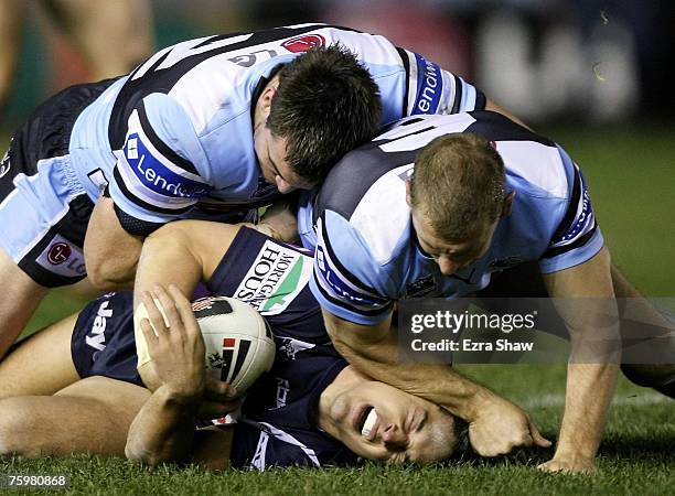 Billy Slater of the Storm is hit by Adam Dykes and Luke Douglas of the Sharks during the round 21 NRL match between the Cronulla-Sutherland Sharks...