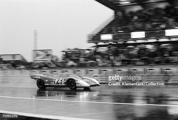The Porsche 917K of Richard Attwood and Hans Hermann passes the pits in a sheet of spray on the way to winning the Le Mans 24 Hours race, Le Mans,...