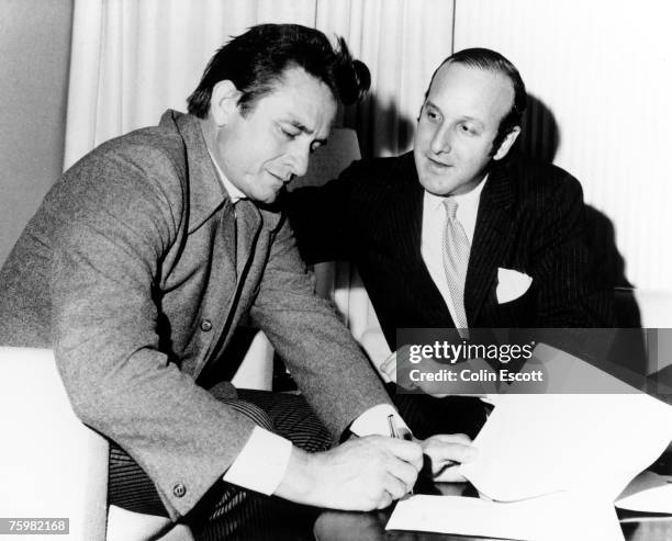 Country singer Johnny Cash signs a record contract with Columbia Records lawyer Clive Davis in circa 1960. He originally signed to Columbia in 1958,...