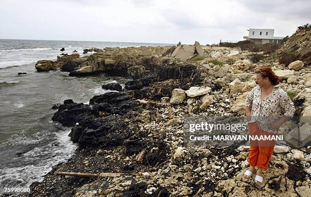 Fifi Kallab, an official from the non-governmental organisation Byblos Ecologia, looks at sea rocks covered with layers of black oil at the coast of...