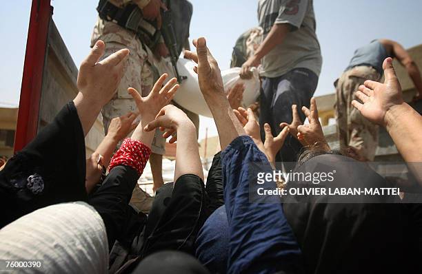 Iraqi women raise their hands to receive humanitarian aid from the Iraqi Ministry of Trade in Baquba, 60 kms north of Baghdad, 05 August 2007. As...