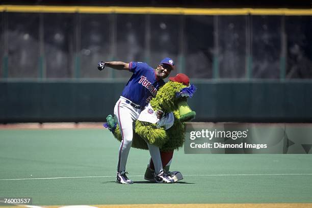 Outfielder Joe Carter of the Toronto Blue Jays throws a playful swing at the Philly Phanatic the mascot for the Philadelphia Phillies prior to a game...