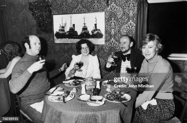 Four friends raise a glass during a meal at Sloop John B's at Chelsea Pier, 10th November 1974.