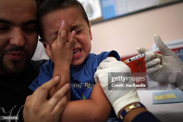 Michael Valdivia holds, Jakob Gutierrez as he receives an immunization shot from school nurse Barbara Dale on August 8, 2007 in Hialeah, Florida. The...