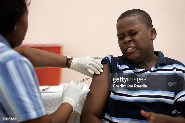 Wilson Fenelon reacts as Josette Thomas, a school nurse, gives him an immunization shot August 8, 2007 in Hialeah, Florida. The free immunization is...
