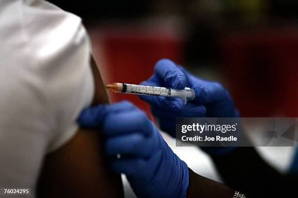 Josette Thomas, a school nurse, gives a child an immunization shot August 8, 2007 in Hialeah, Florida. The free immunization is part of the...