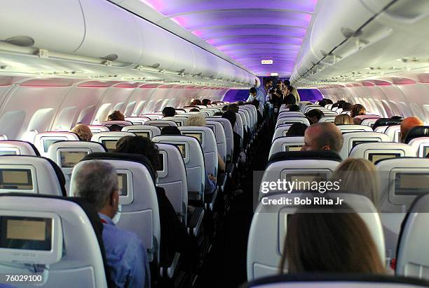 Passengers in custom-designed leather chairs enjoy Virgin America airlines mood-lit cabins and in-flight entertainment system which includes...