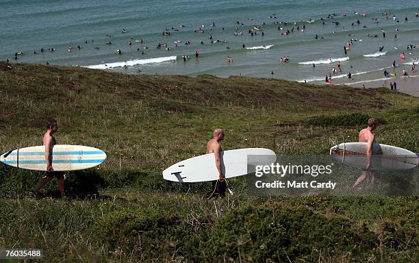 Three surfers walk along the coast path above Watergate Bay close to the site of the Ripcurl Boardmasters at Fistral Beach on August 9 2007 in...