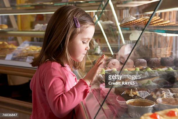 young girl (9-11) looking at cakes in display cabinets, side view - bakery display stock-fotos und bilder
