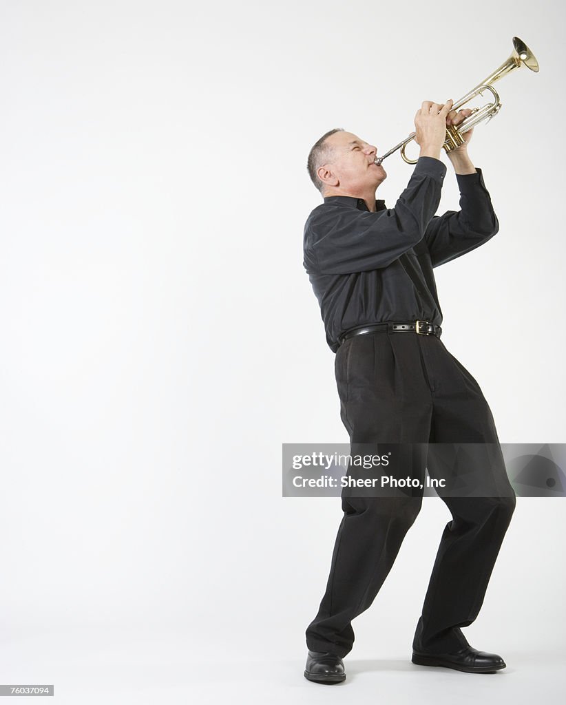 Man playing trumpet, against white background