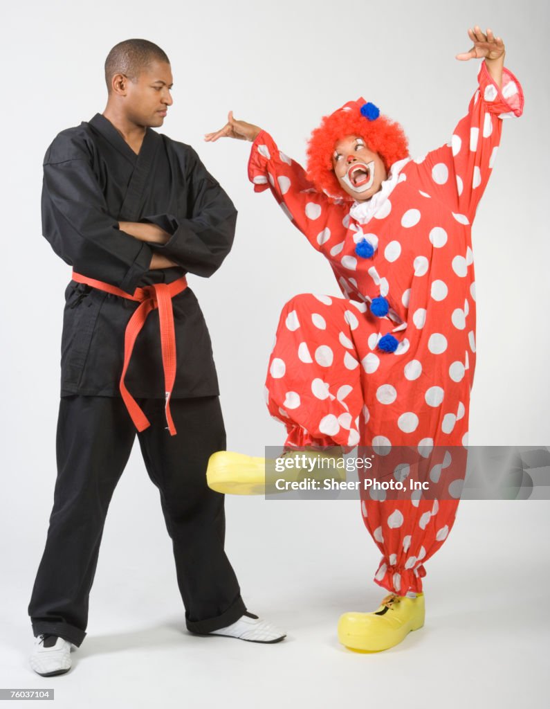Man wearing karate uniform looking at clown gesturing