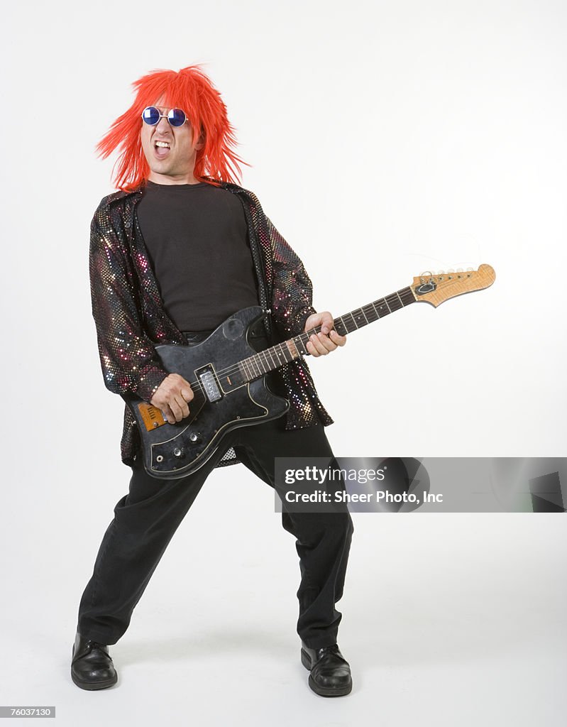 Man in orange hair playing electric guitar, portrait