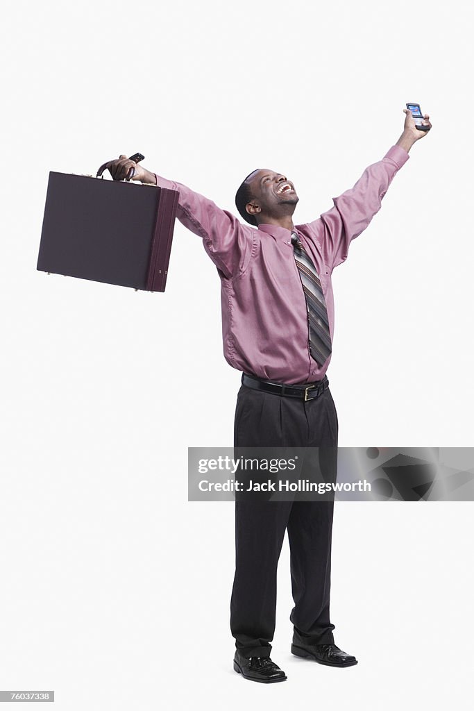 Young businessman raising hands with briefcase and mobile phone