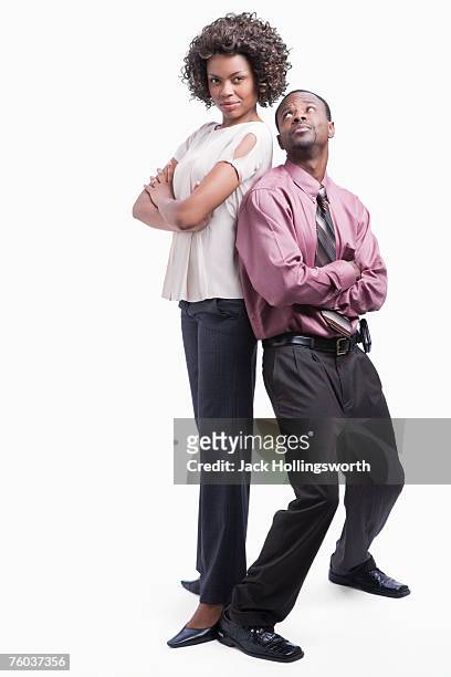 businessman and woman standing back to back against white background - short guy tall woman stock pictures, royalty-free photos & images