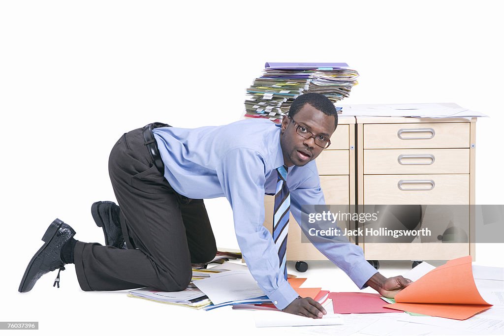 Portrait of young business man picking up folders from floor