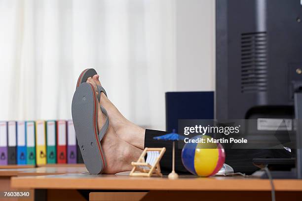 man wearing flip flops with feet up on desk in office, low section - flip flop stock-fotos und bilder