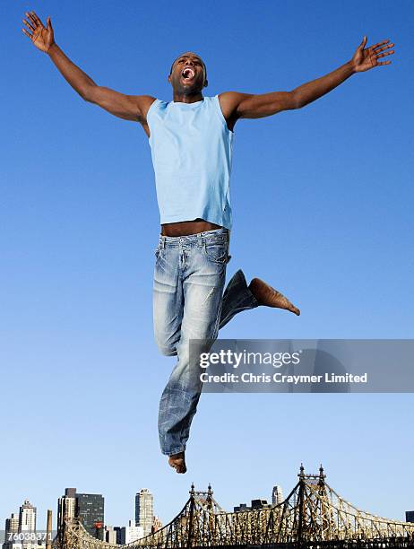 man jumping mid air, city skyline in background, low angle view, digital composite - man arms outstretched stock pictures, royalty-free photos & images