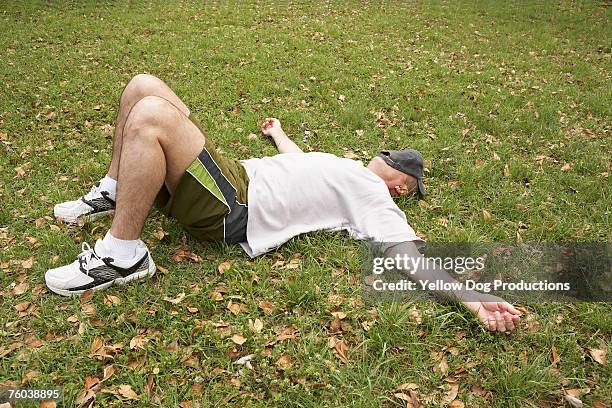 man resting on grass with hat covering face - man sleeping with cap stock pictures, royalty-free photos & images