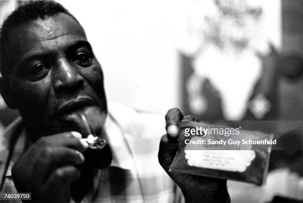 Blues musician Howlin' Wolf lights his pipe while holding up a package of Edgeworth tobacco in a hotel room in July 1968 in San Francisco, California.