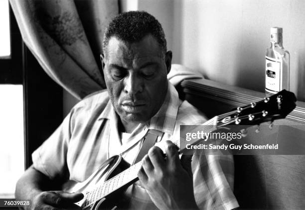 Blues musician Howlin' Wolf poses for a portrait with an Epiphone hollowbody electric guitar in front of a bottle of Jose Cuervo tequila in a hotel...