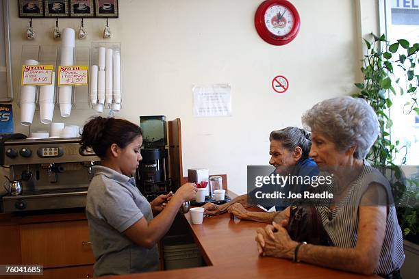 Arlen Tellez, originally from Nicaragua, serves Cuban espresso to two women August 9, 2007 in the Little Havana neighborhood of Miami, Florida....