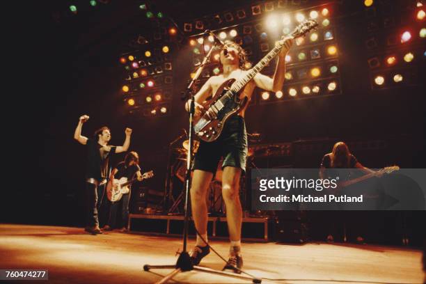 Guitarist Angus Young performing with heavy rock group, AC/DC, London, 1980. Left to right: Brian Johnson, Malcolm Young, Angus Young and Cliff...