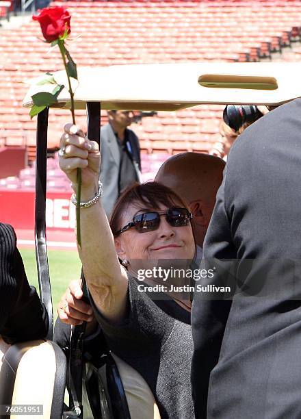 Geri Walsh, wife of former 49ers coach Bill Walsh, waves a single rose to fans as she leaves the stadium during a public memorial service for Walsh...