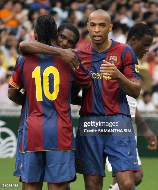 Barcelona's Thierry Henry celebrates with teammates Ronaldinho and Samuel Eto after the team scores against local club Happy Valley-Kitchee during...