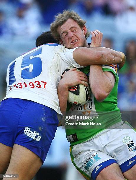 David Howell of the Raiders is tackled by Nick Kouparitsas of the Bulldogs during the round 22 NRL match between the Bulldogs and the Canberra...