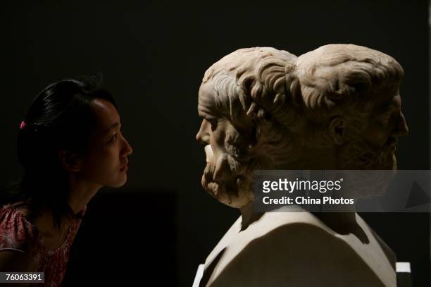 Visitor views a sculpture of Aristophanes and Sophocles during an exhibition of ancient Greek art from the Louvre Museum on August 11, 2007 in...