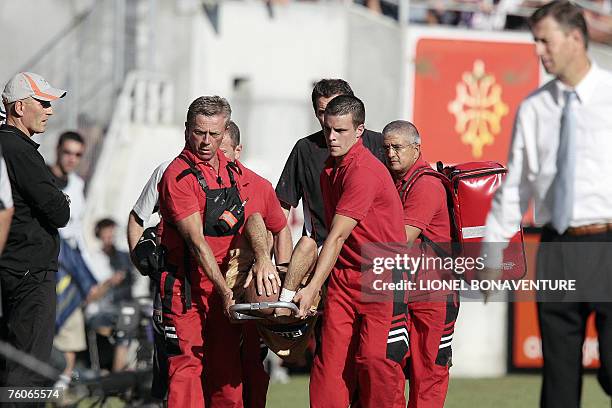 Lyon's Brazilian defender Cris is carrying on a stretcher after being injured as Toulouse's and Lyon's coaches Elie Baup and Alain Perrin look on,...
