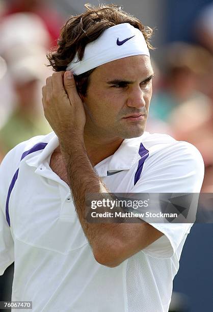 Roger Federer of Switzerland adjusts his headband between points against Novak Djokovic of Serbia during the final of the Coupe Rogers at Stade...