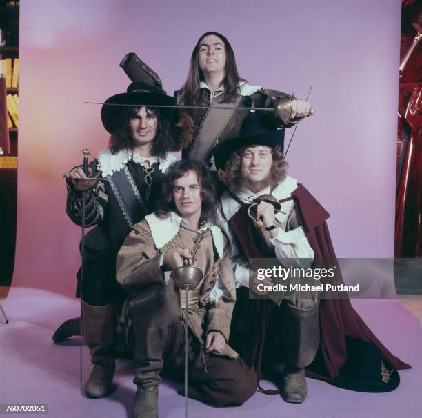 Studio portrait of English rock group Slade, posing in cavalier costumes and holding swords, London, 1974. Clockwise, from front: bassist Jim Lea,...