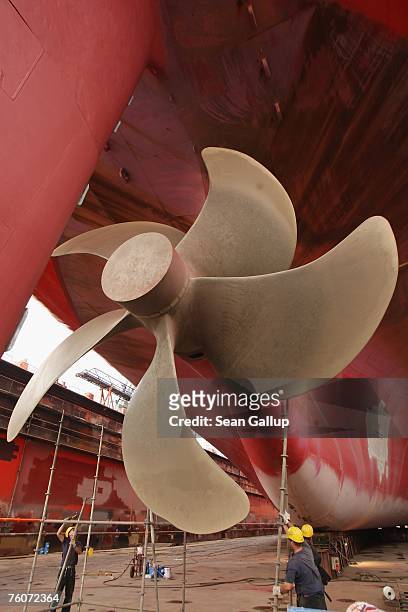 Workers finish maintenance work on a cargo ship's propeller during repairs of the ship at the Blohm & Voss shipyard August 13, 2007 in Hamburg,...