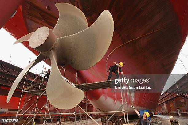 Workers remove scaffolding after maintenance work on a cargo ship's propeller during repairs of the ship at the Blohm & Voss shipyard August 13, 2007...