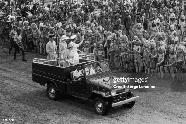 Mark Phillips, Princess Anne, Queen Elizabeth II and Prince Philip waving to Asaro Mudmen from a jeep during a royal tour of Papua New Guinea,...