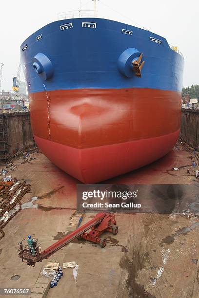 Worker drives a crane toward the hull of a ship undergoing maintenance and repairs at the Blohm & Voss shipyard August 13, 2007 in Hamburg, Germany....