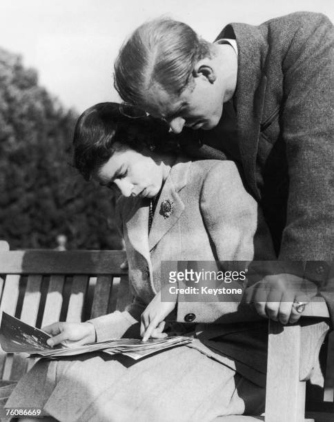 Princess Elizabeth and her husband, Philip Mountbatten, study their wedding photographs while on honeymoon in Romsey, Hampshire, November 1947.